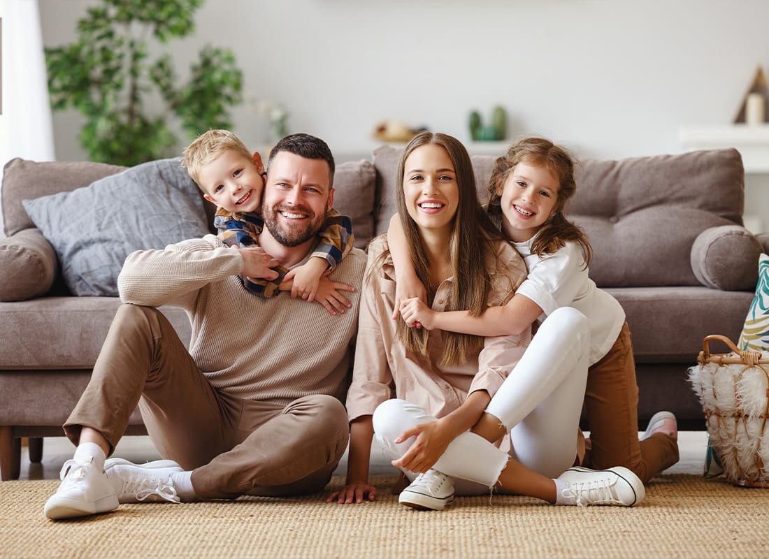 Personal Insurance - Happy Family of a Mother Father and Children at Home on a Couch